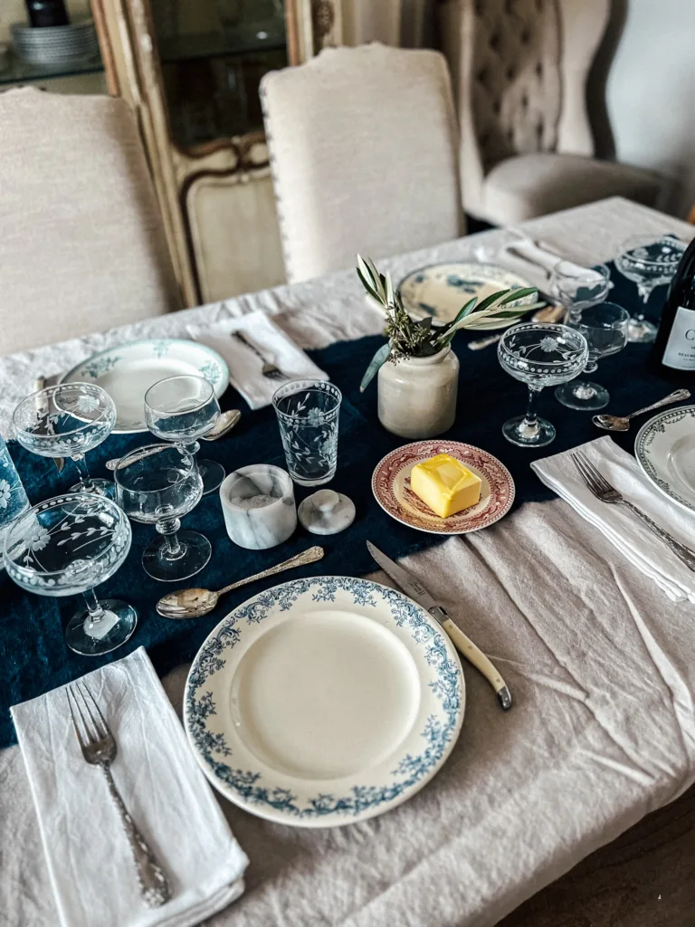 Glassware, plates, silverware on a navy table runner.