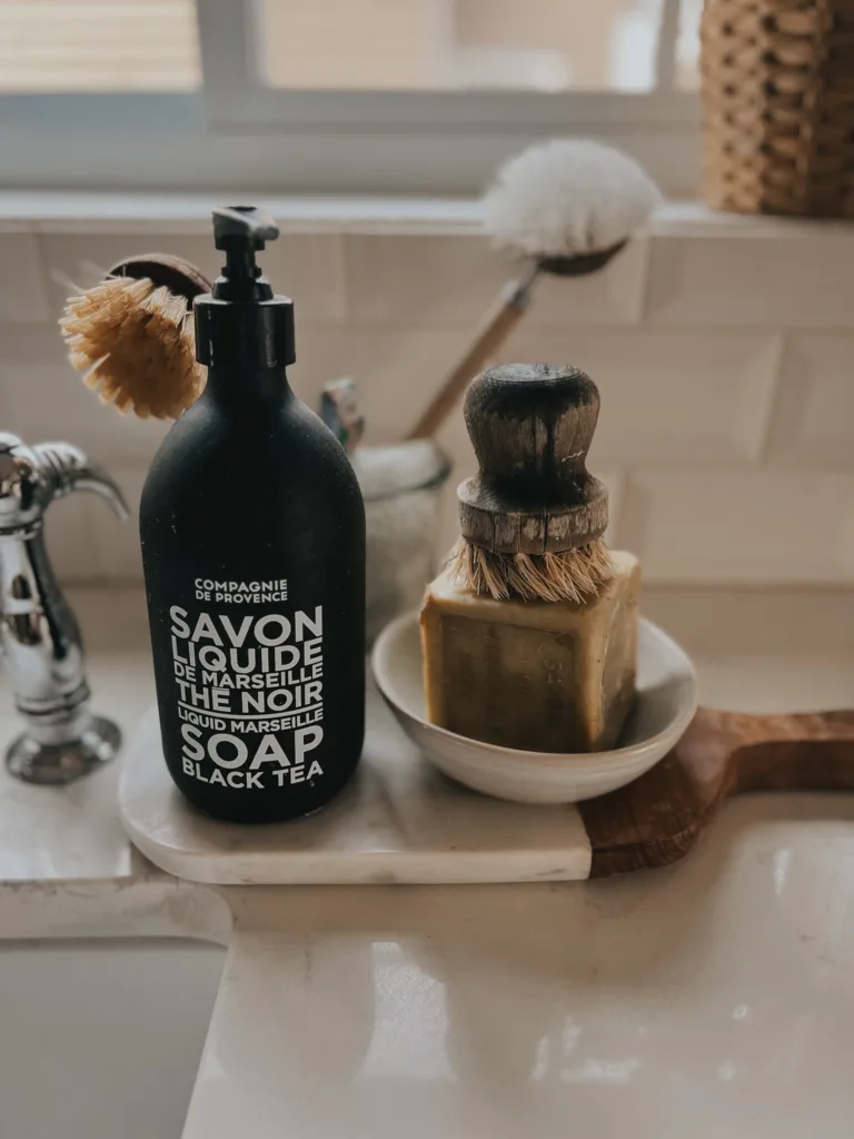French hand soap and pot scrubber sitting on a kitchen counter.
