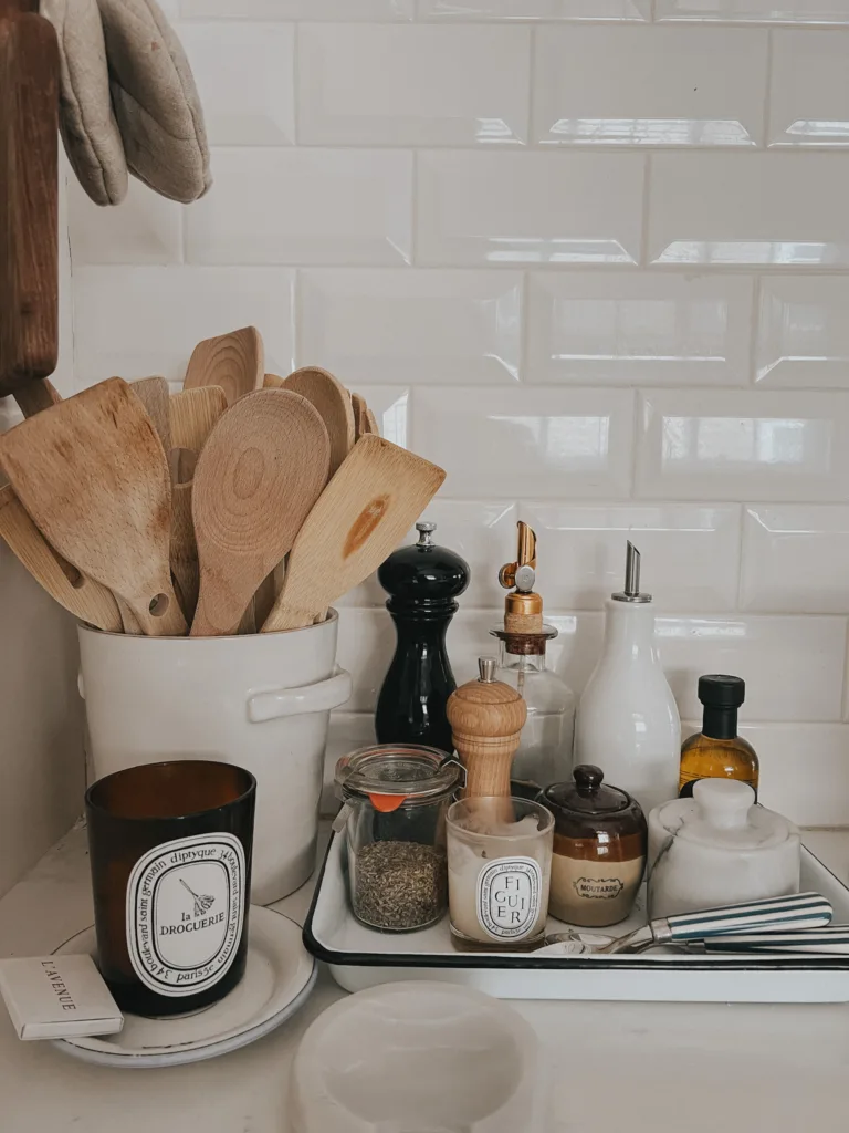 Wooden spoons in a white canister. Diptyque candle sitting on the counter. 