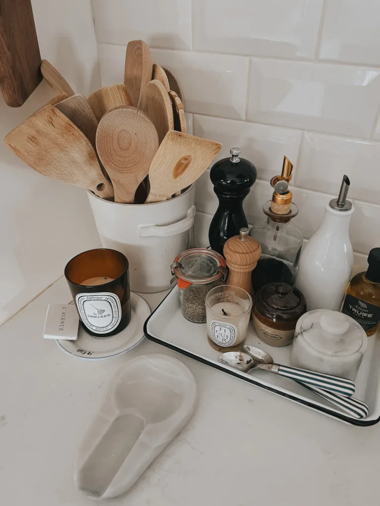 Diptyque Candle on a counter with woodens spoons, pepper mill, and salt cellar.