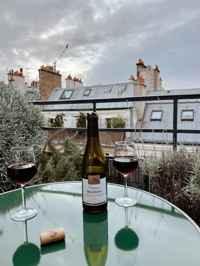 Wine bottle with two wine glasses sitting on green table in paris.