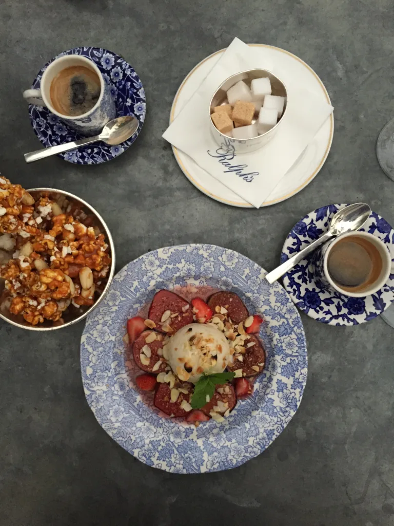 Blue and white plates with strawberries, blue and white cup and saucer and bowl of sugar cubes at Ralphs in Paris. Part of essential guide to saint germain des pres.