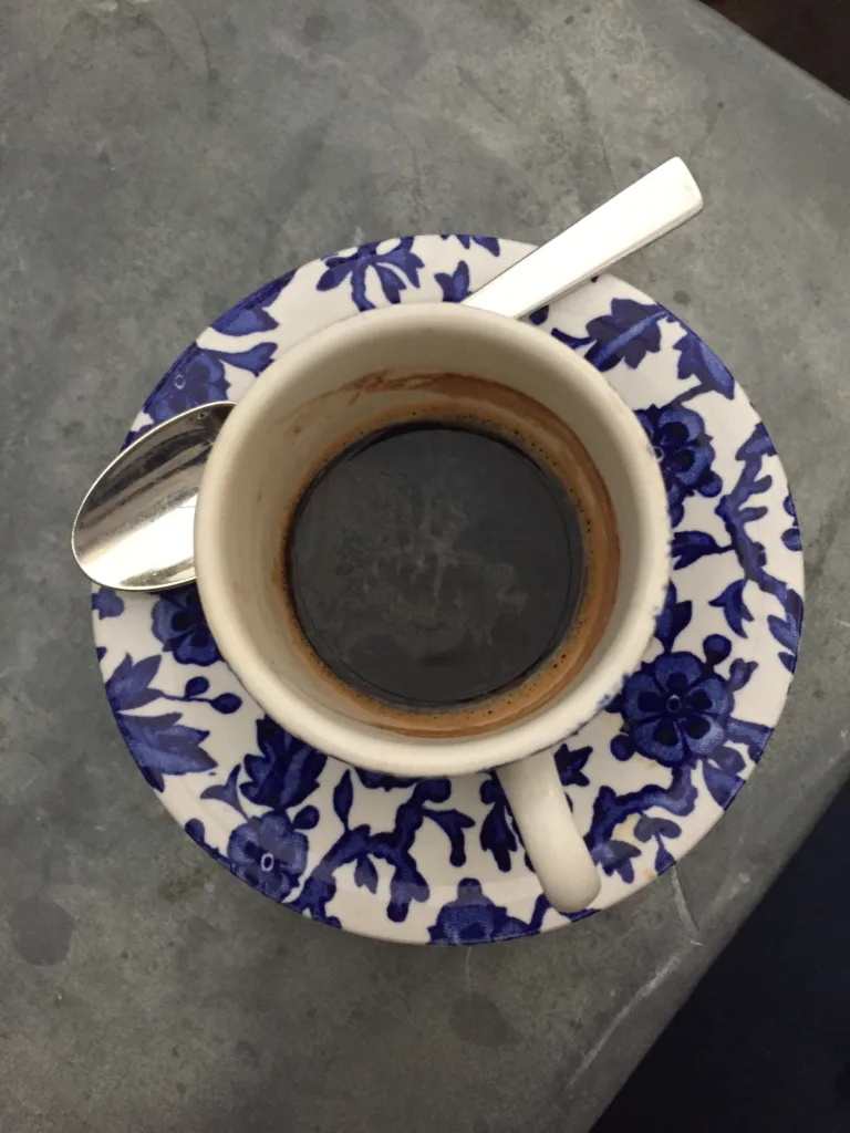 Blue and white espresso cup and saucer sitting on a counter.