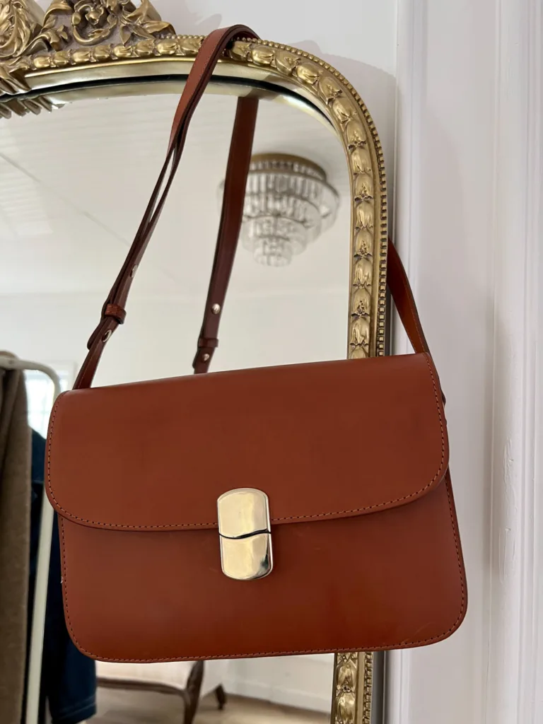 Brown leather handbag hanging from a mirror.