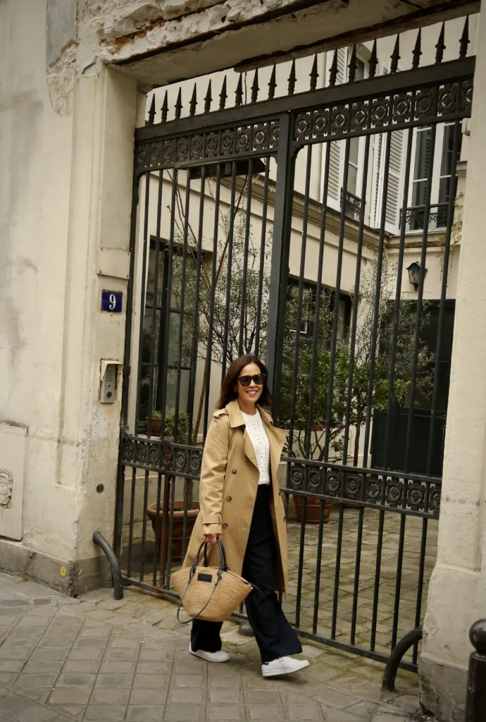 woman wearing sezane trench coat like a french girl with navy slacks and sneakers.