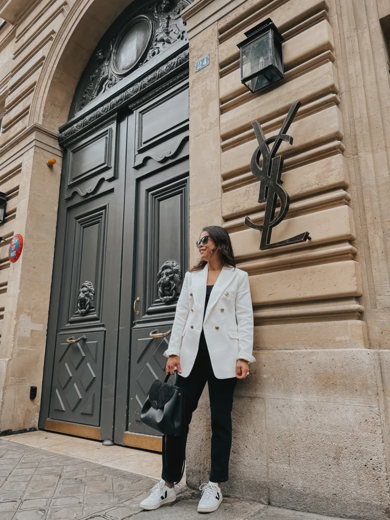 Favorite French Inspired Blazers | Lady wearing white blazer, black jeans, and sneakers.