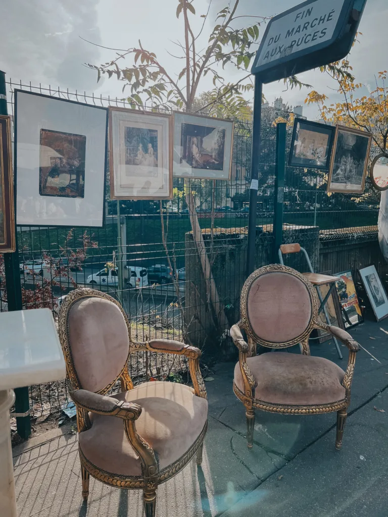French chairs and paintings hung up at a flea market on the street.