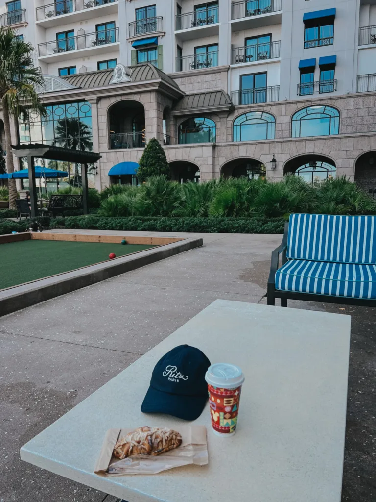 Ritz Paris hat, croissant, and coffee sitting on a table at Disney's Riviera Resort.