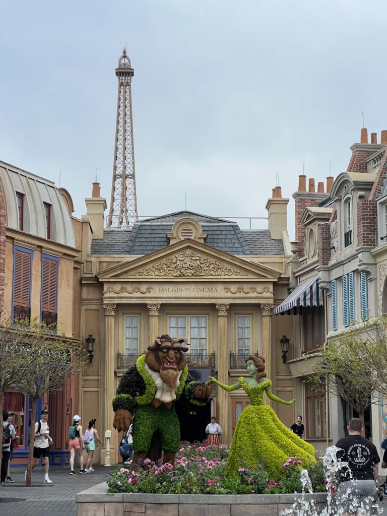 Beauty and the beast characters at Epcot dressed with flowers in front of the eiffel tower.