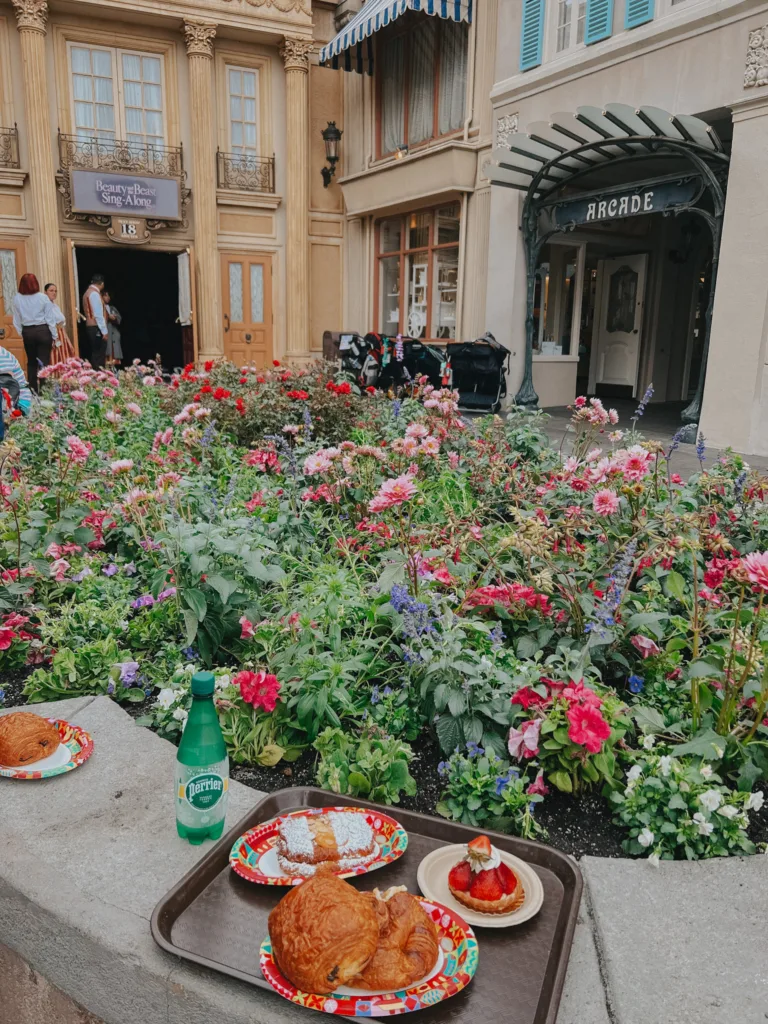 Flowers at Epcot with tray of croissants and bottled water sitting nearby | French inspired things at Disneyworld