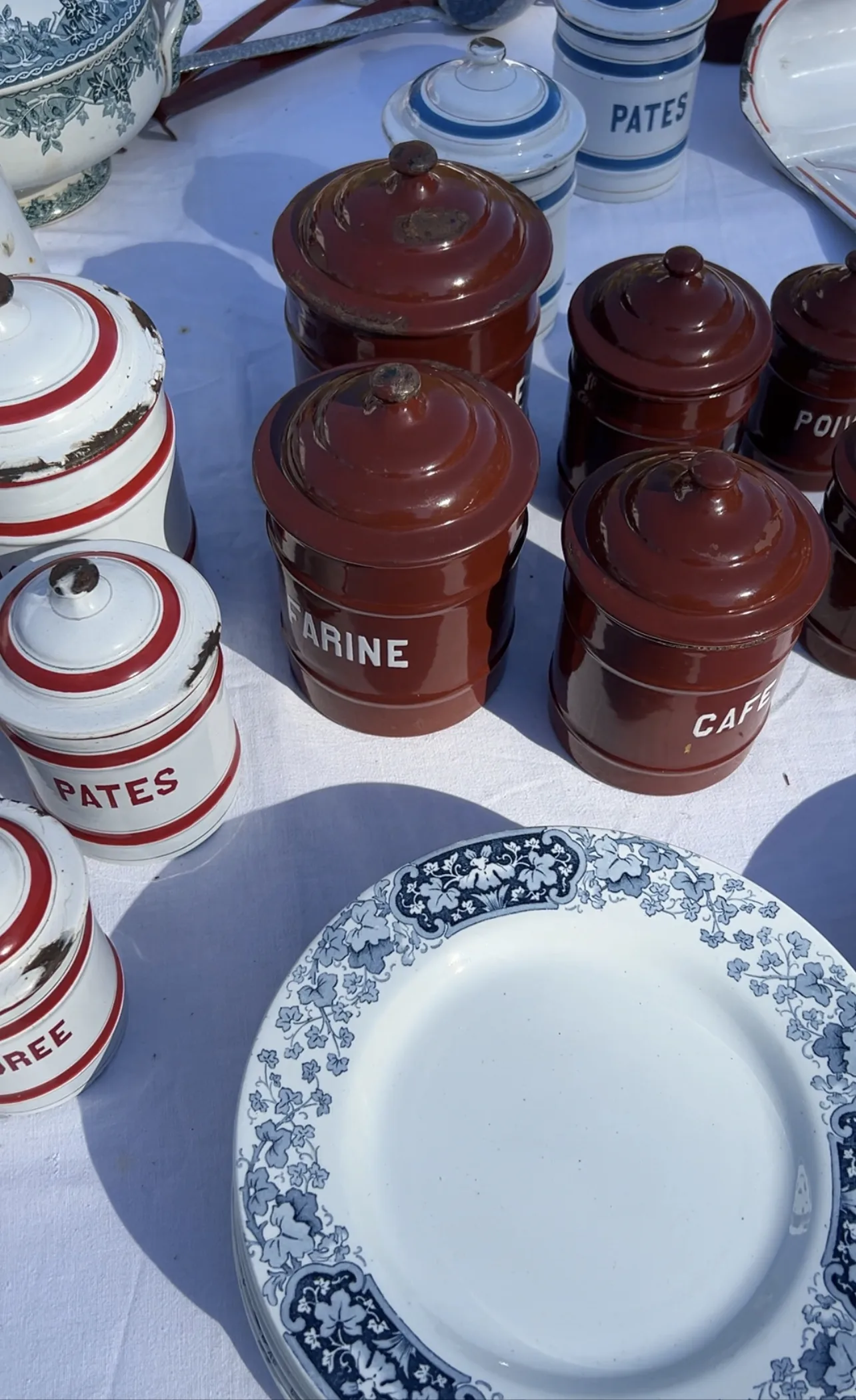 Antique plates and cannisters sitting on a table.