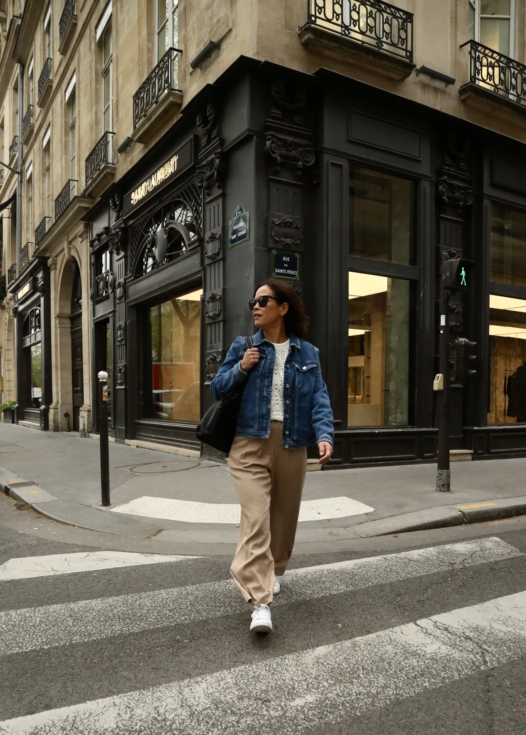 Woman wearing pants, sneakers, and denim jacket.