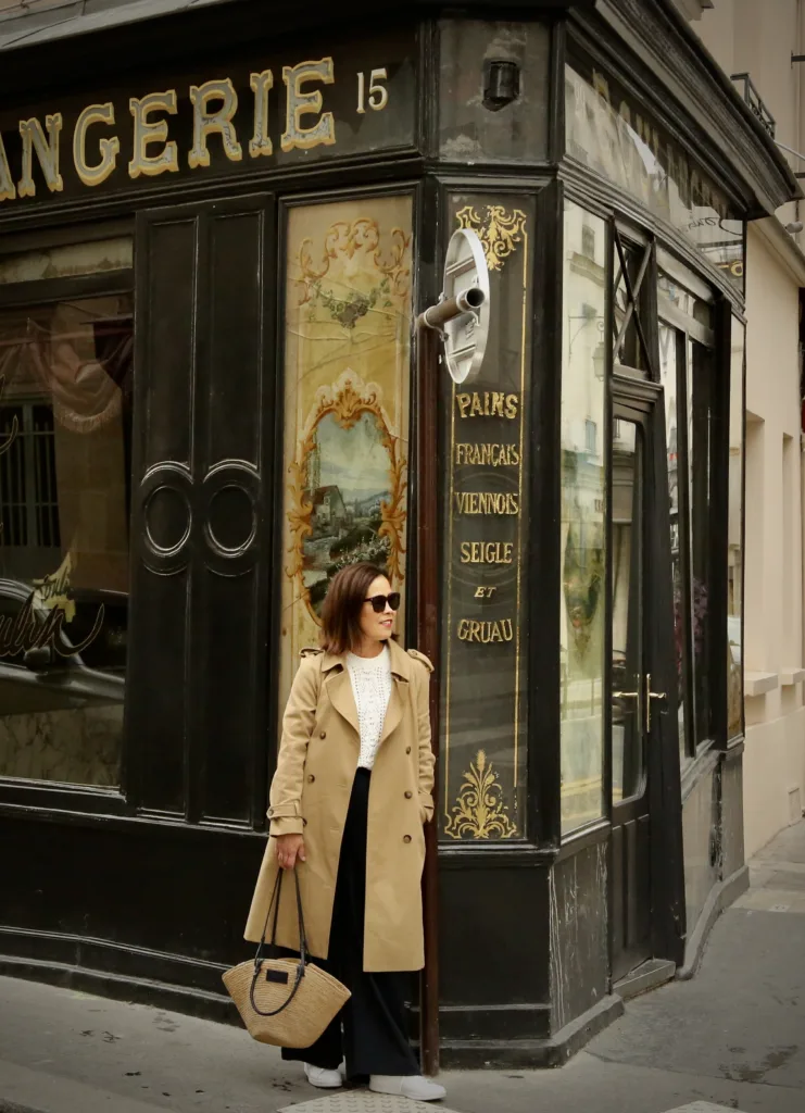 Woman wearing trench coat standing in front of black building.