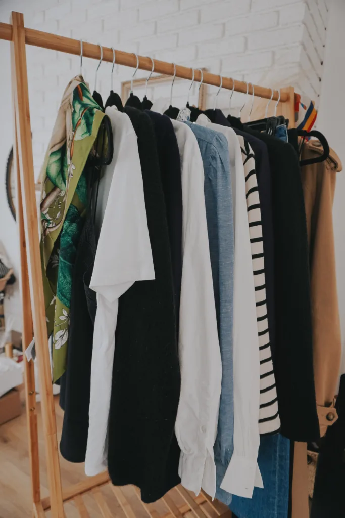 Pieces of clothing on a wooden clothing rack for what to pack in a carry-on for Paris.
