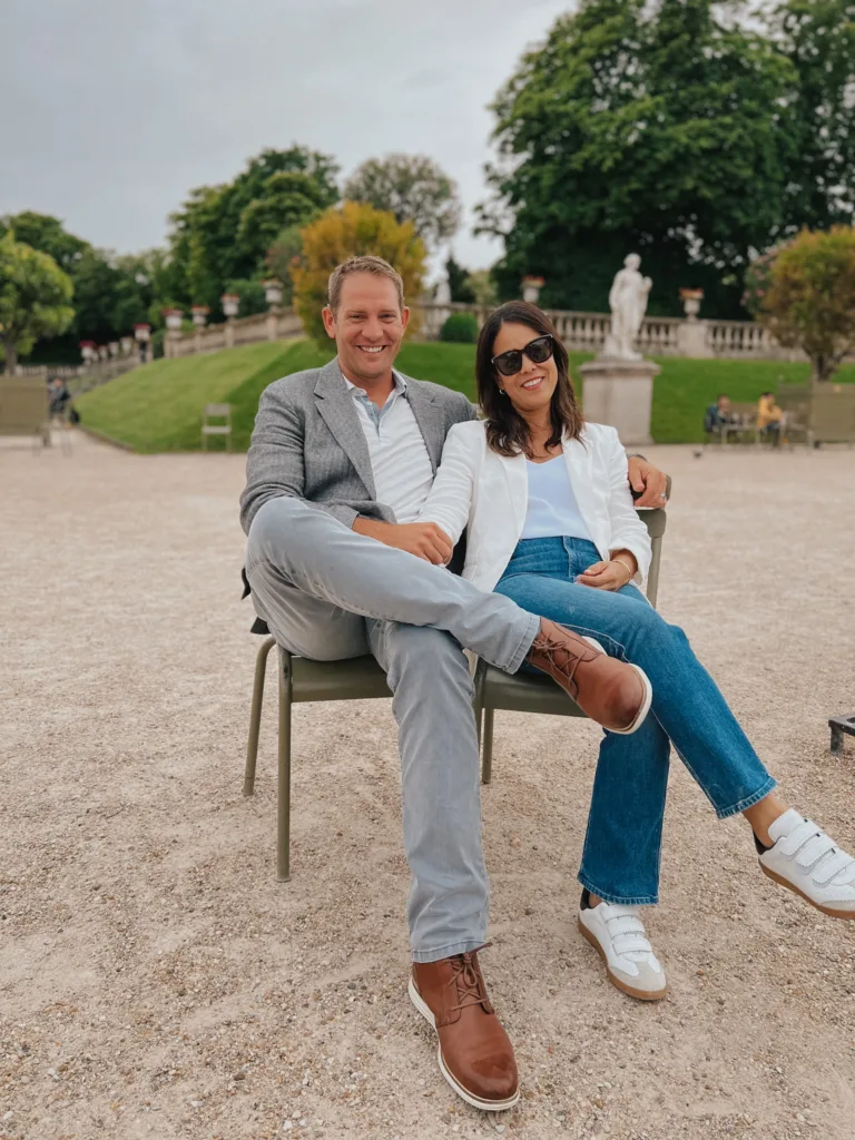 Man and woman sitting in park in Paris showing what to wear in Paris for men.