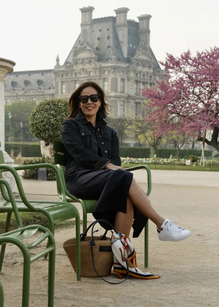 Woman wearing sneakers and dress sitting in park in Paris.