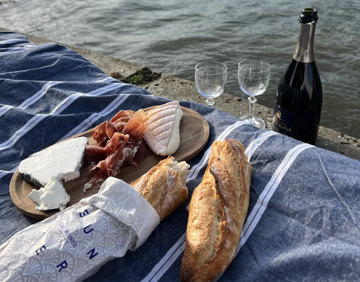 Baguette and cheese on a blanket in Paris.
