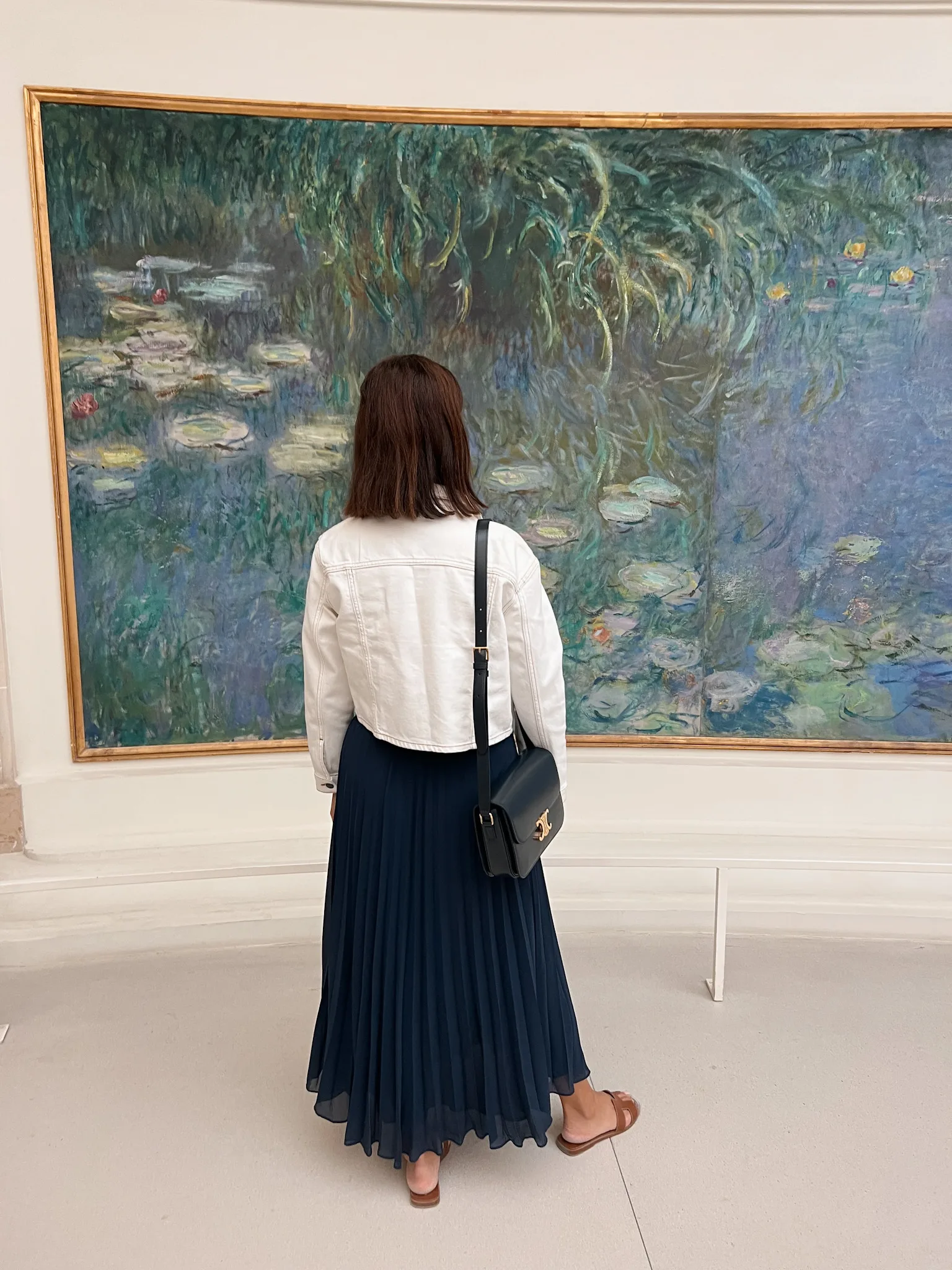 Woman standing in front of Monet water lily painting in Paris.