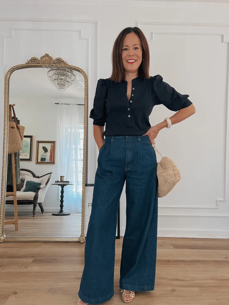Lady wearing wide leg jeans, raffia bag and gold sandals.