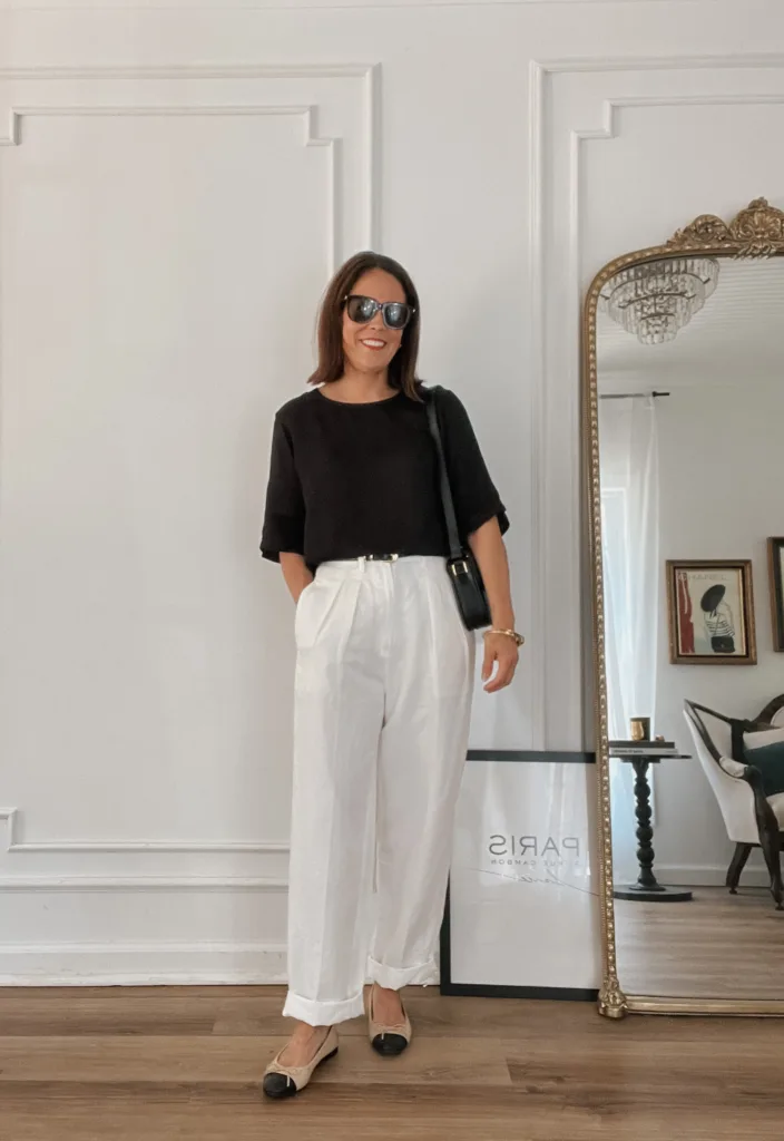 Woman wearing white pants, black top, and sandals.