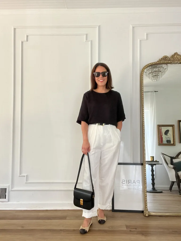 Woman wearing black top with white pants.