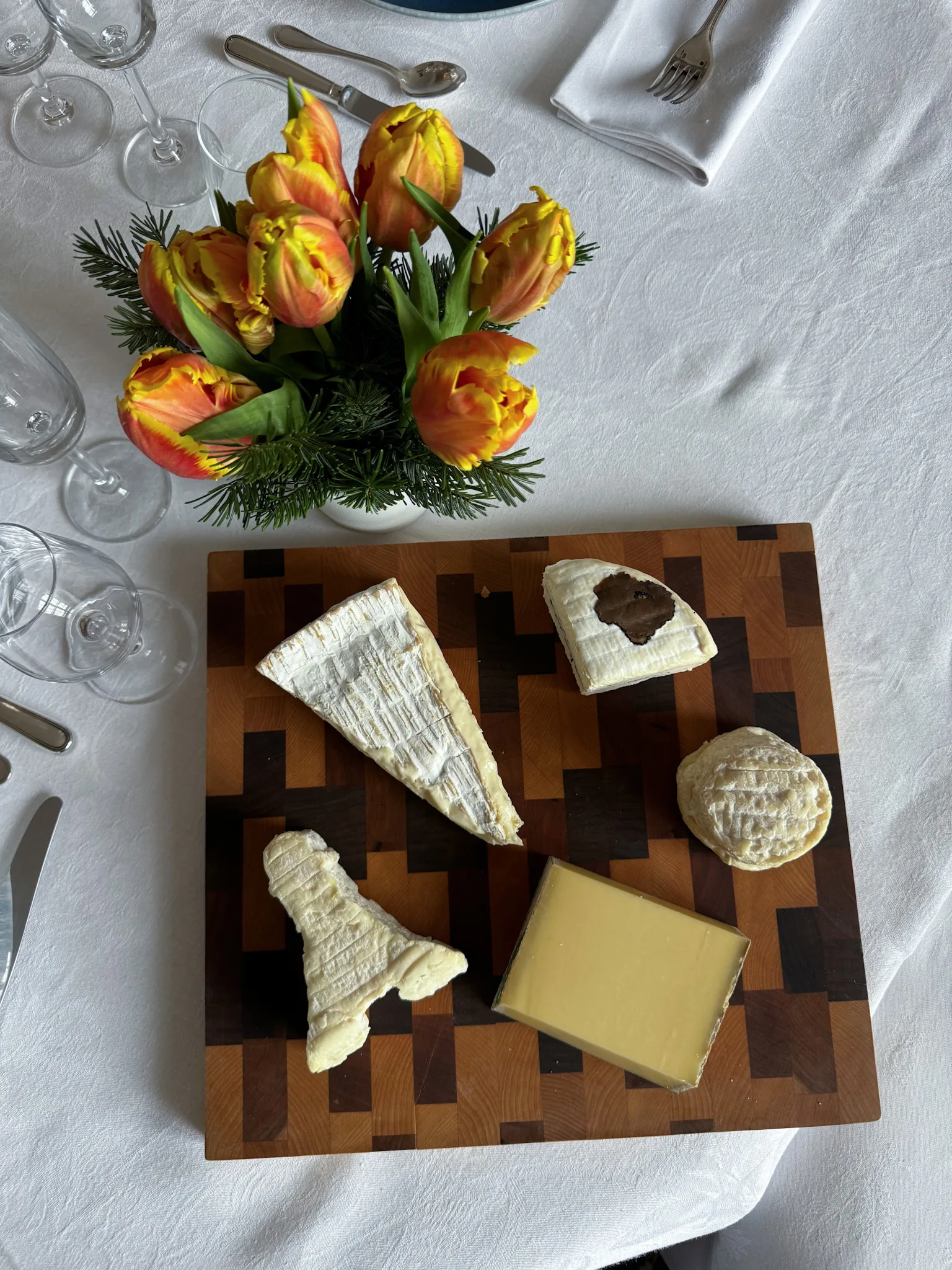 Different types of cheese on a board sitting on a table for what french people eat.