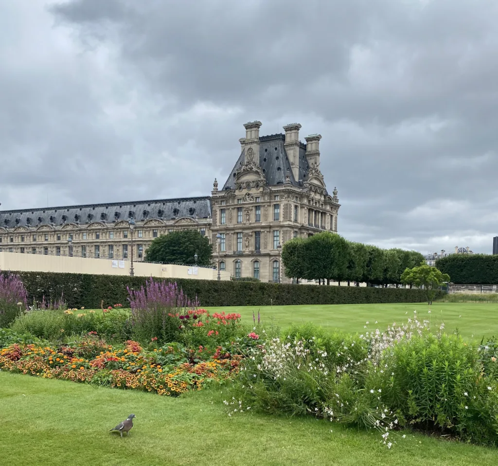 Picture of the Louvre in Paris in background with flowers and birds.