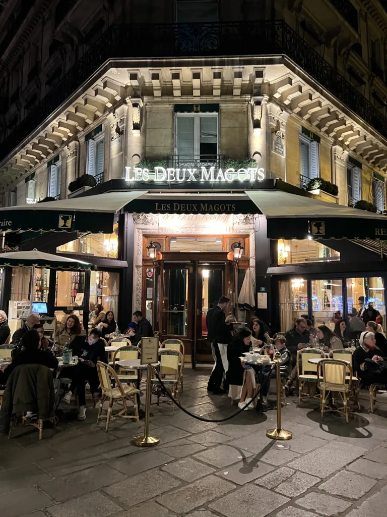 People sitting outside cafe in Paris at night.