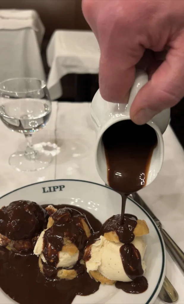 Man pouring chocolate sauce over profittereles