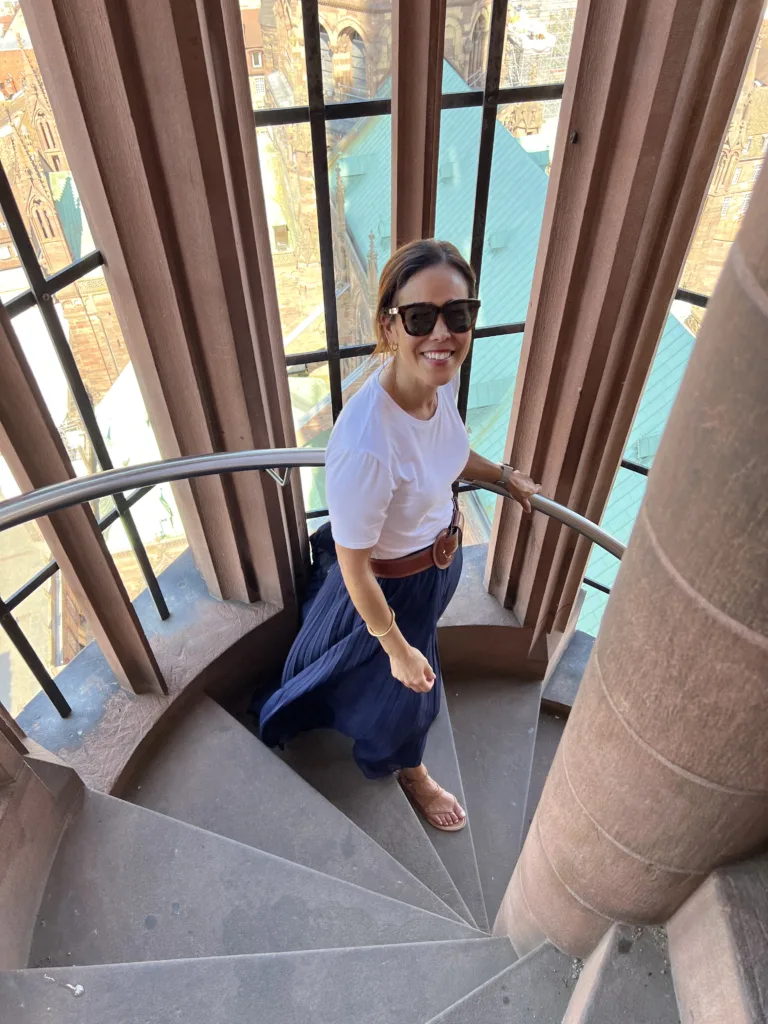 navy skirt with white tee and belt Woman walking down the stairs in navy skirt with white tee and belt.