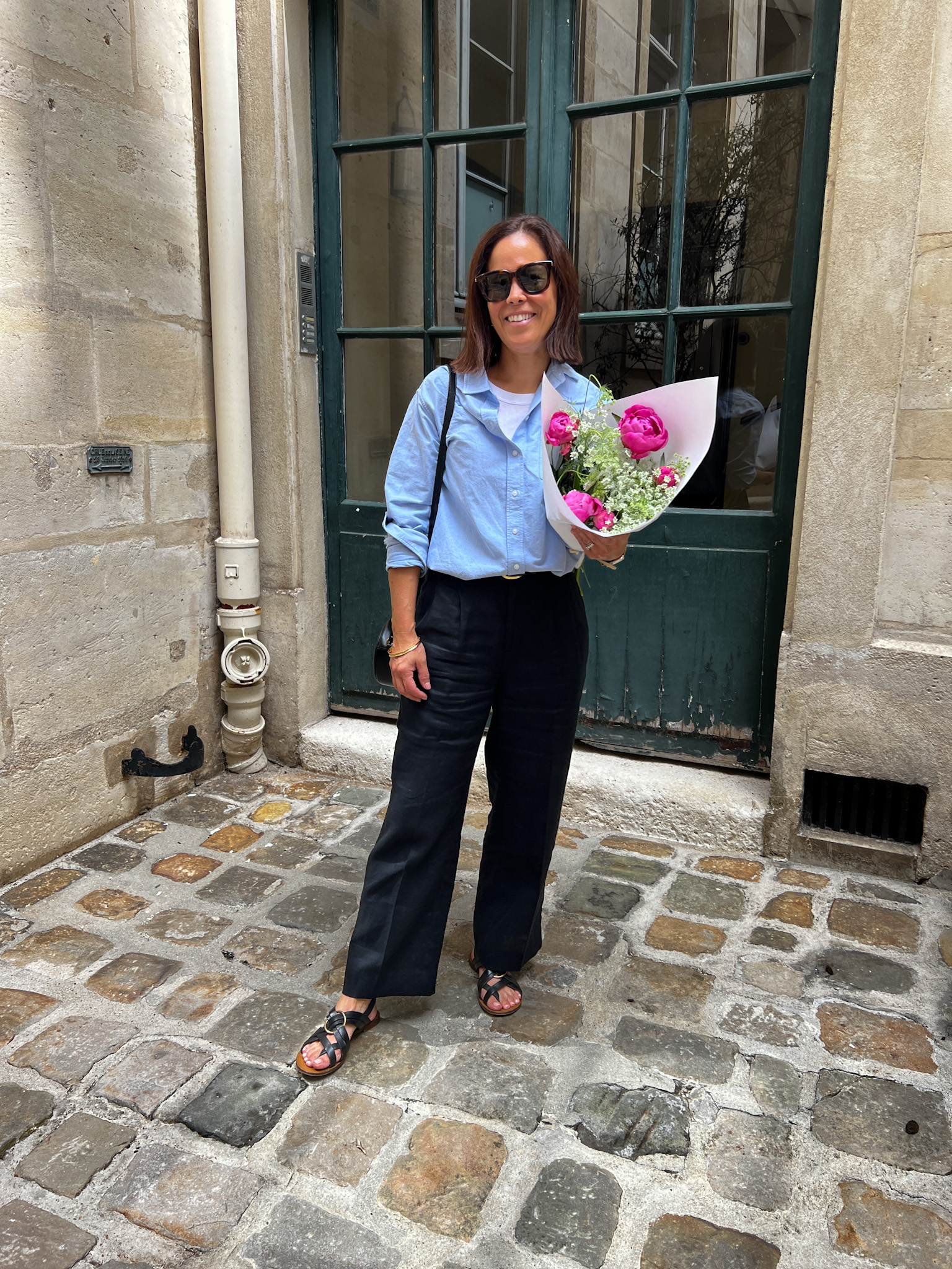 Woman wearing blue top and black jeans with sandals in Paris.