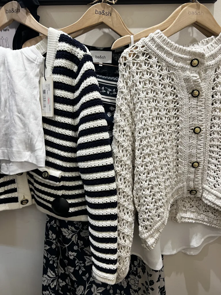 Sweaters hanging up in a closet.