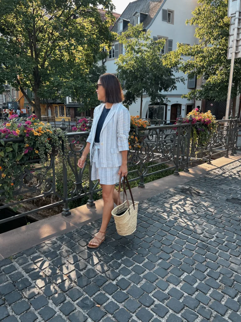 matching shorts and blazer in Paris Woman in navy tee, shorts and blazer walking on a bridge with market tote.