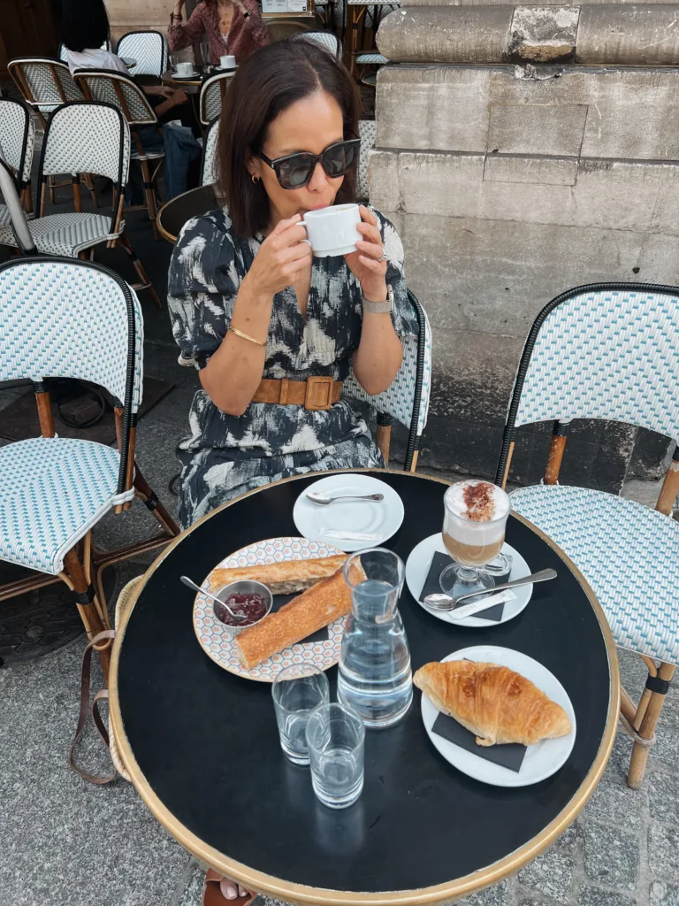 baguette and coffee on table Woman drinking coffee with baguette and coffee on table.
