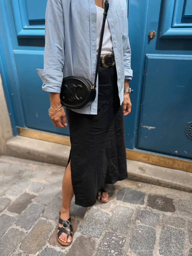 Woman in blue button down standing against a door.