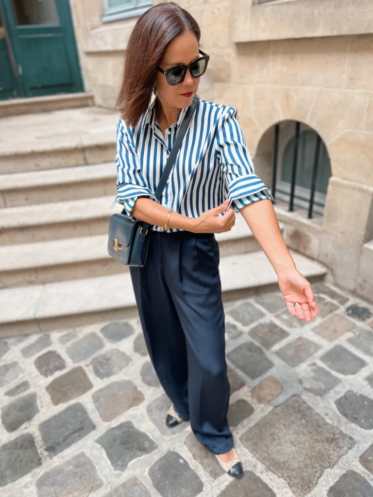 Woman rolling up sleeve wearing silk navy stripe top