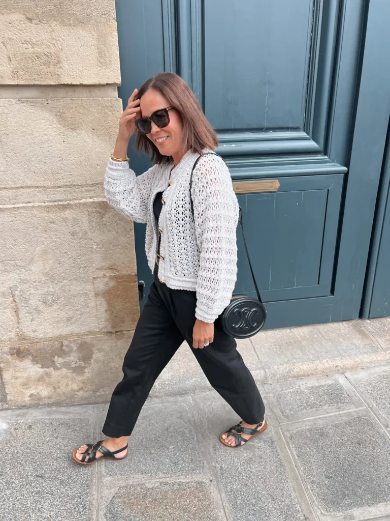 black trousers and cream sweater Woman walking wearing black trousers and cream sweater.