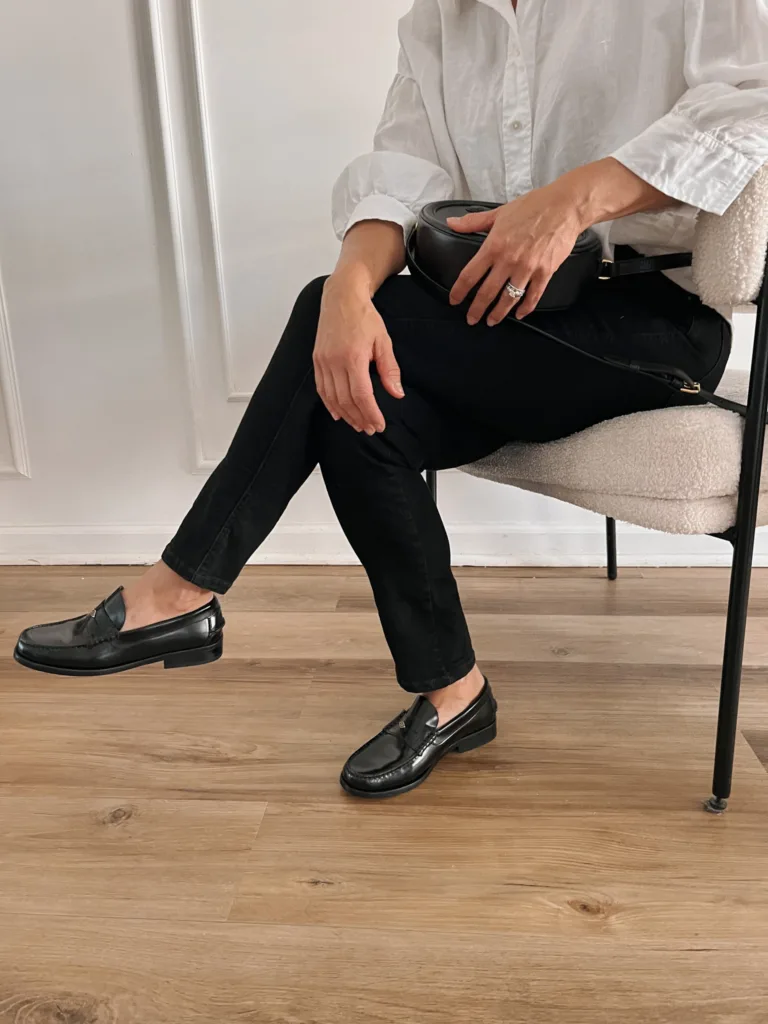 Woman wearing black denim, black loafers, and white button down.