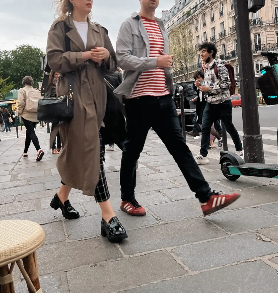 Woman wearing black loafers and trench coat.