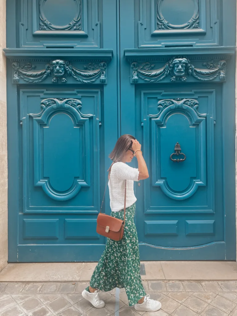 Woman in green skirt with sweater walking in paris for how to wear sneakers like a french girl