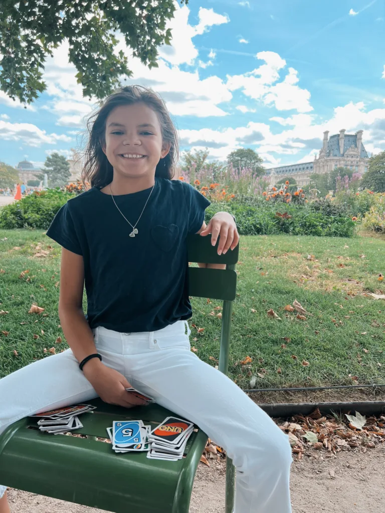 Girl with navy top playing uno in a park in Paris.