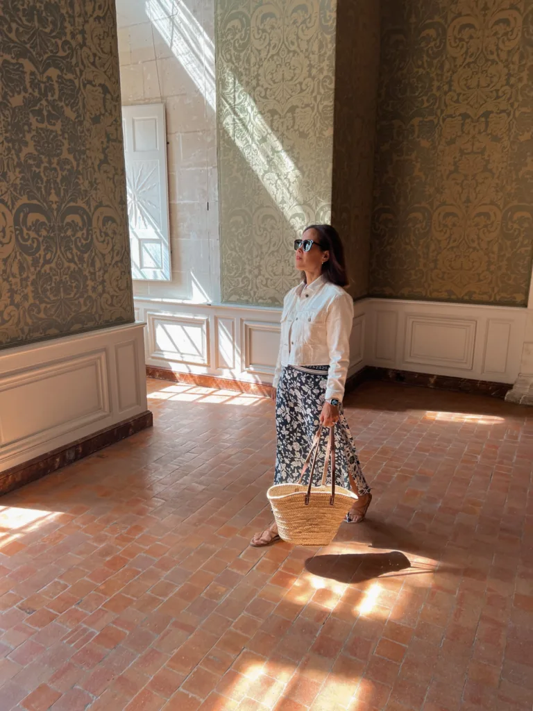 Lady wearing printed skirt with white jacket and market tote.