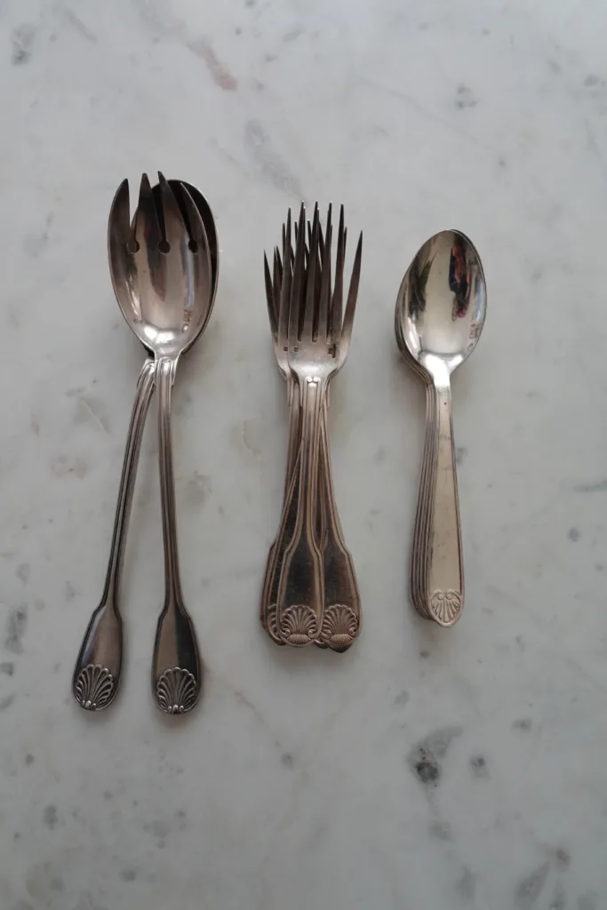Fork, spook, and serving utensils on a marble table.