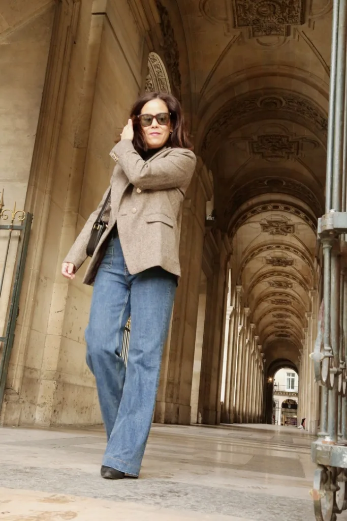 Woman wearing straight leg jeans walking with blazer and boots.