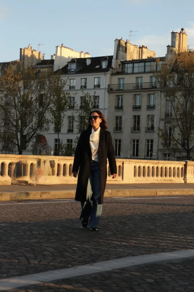 woman wearing navy coat walking across street in Paris in classic French girl inspired winter coat.