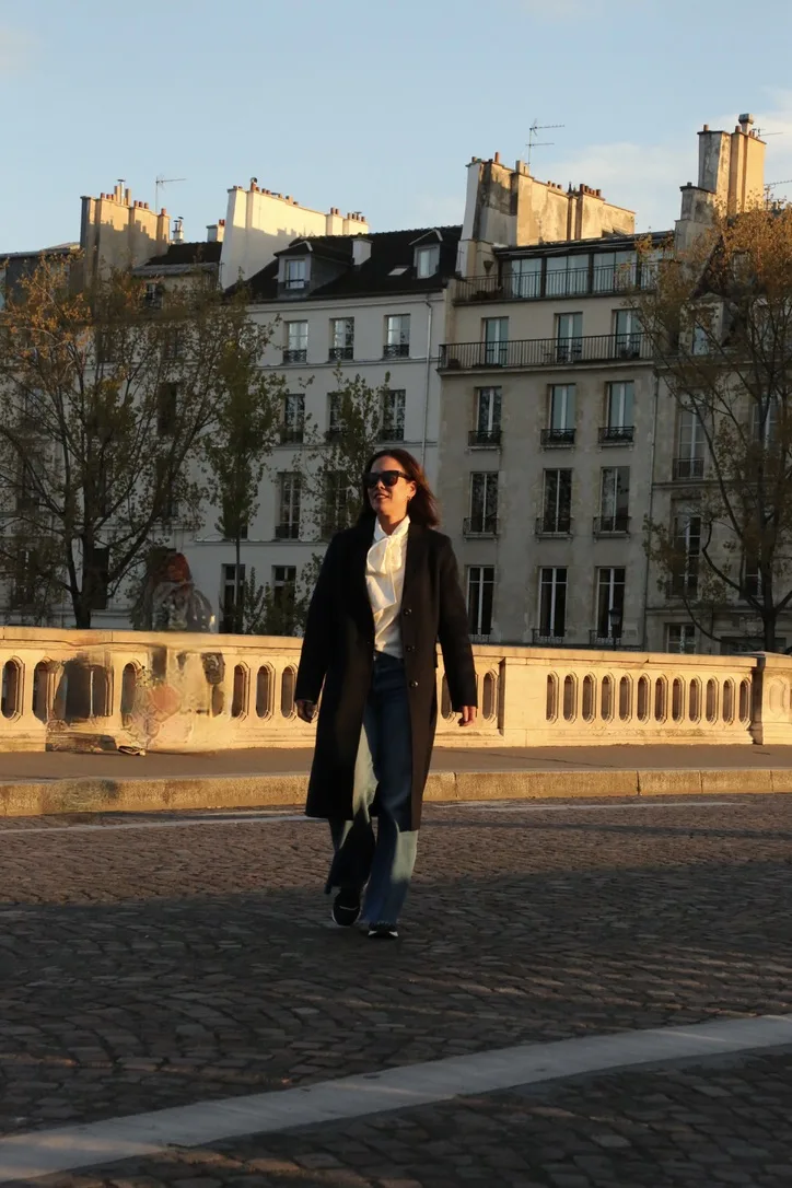 woman wearing navy coat walking across street in Paris in classic French girl inspired winter coat.