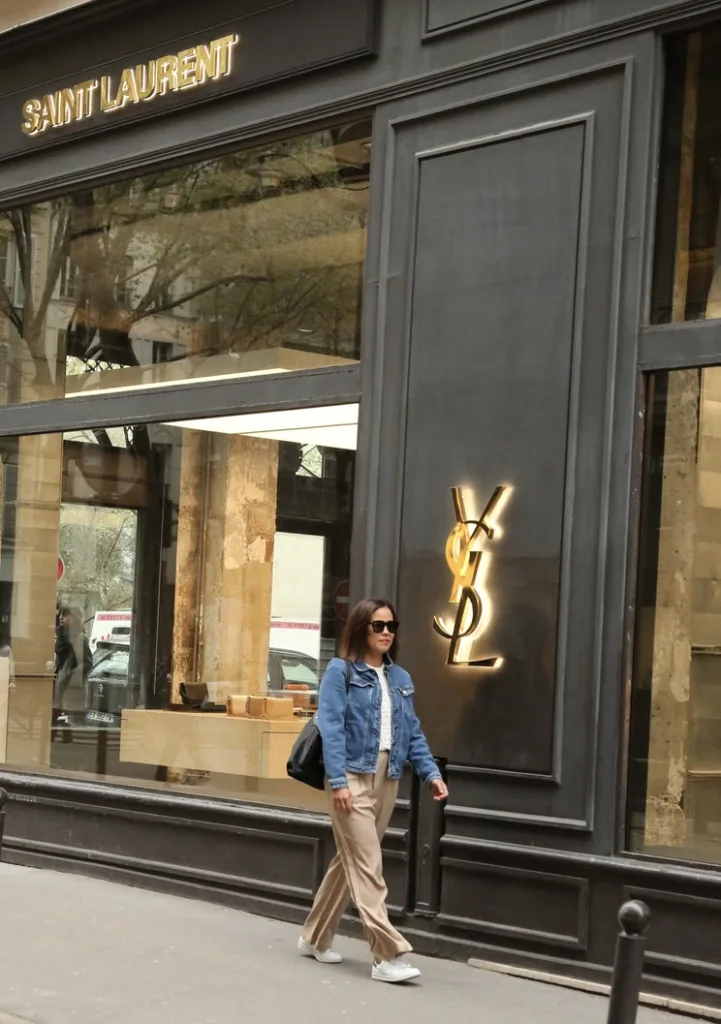 Woman walking wearing trousers, with denim jacket for paris in the fall.