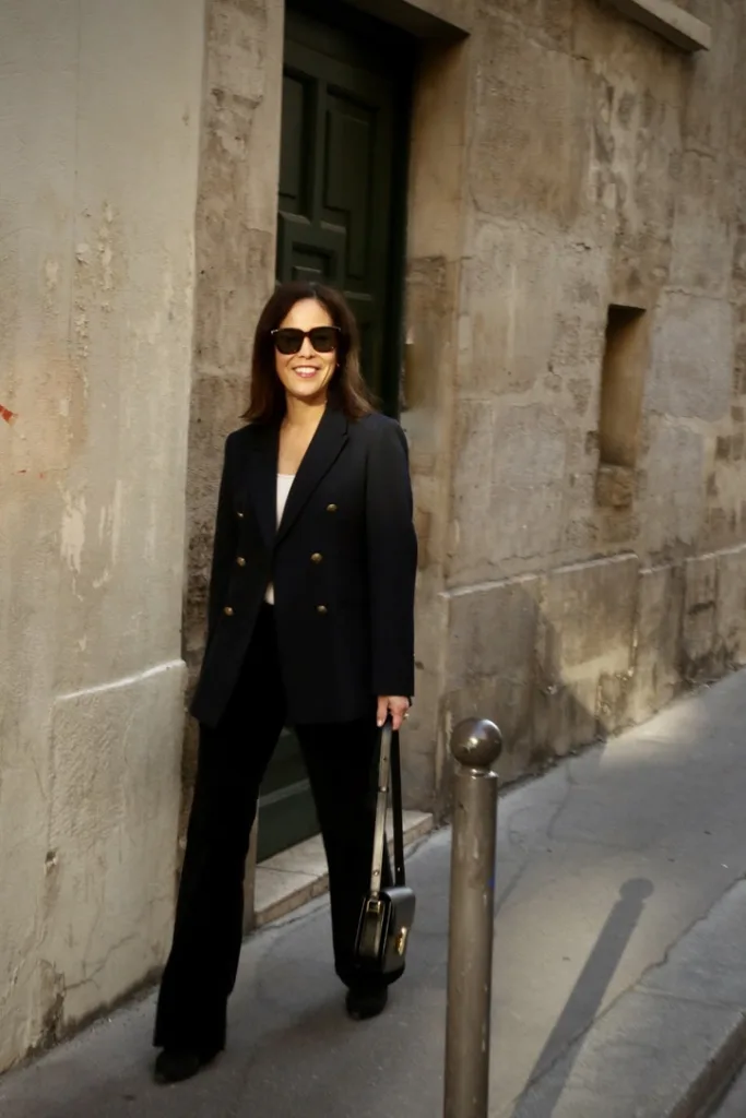 Woman wearing black blazer and denim walking in Paris.