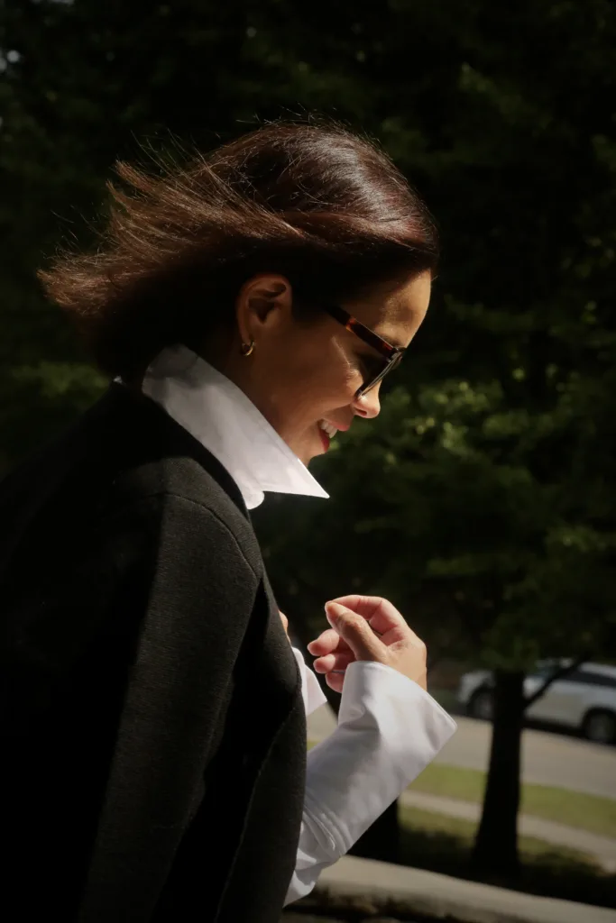 Side profile of woman wearing black cardigan, white button down.