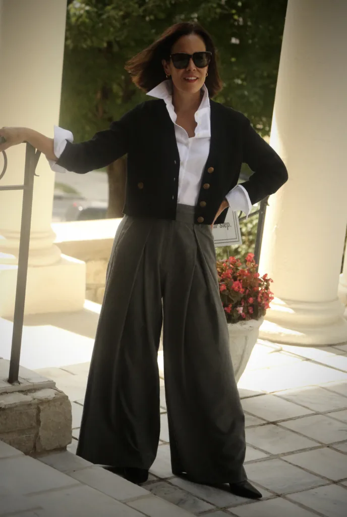 Woman wearing black cardigan with grey trousers standing against a staircase for elevated fall pieces at ME+EM